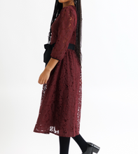 Woman wearing a burgundy lace dress on a white background