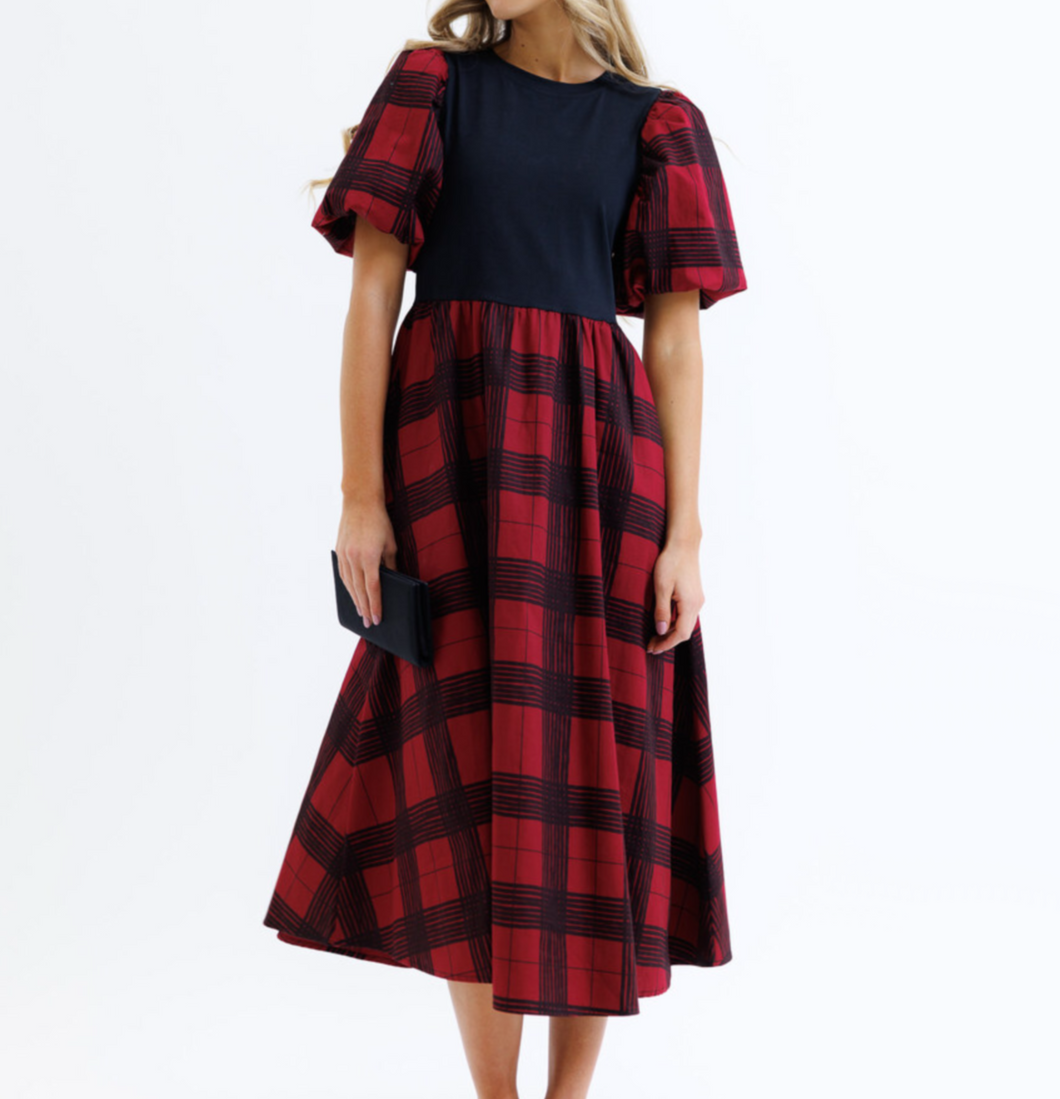 Woman wearing a red and navy checkered dress on a white background